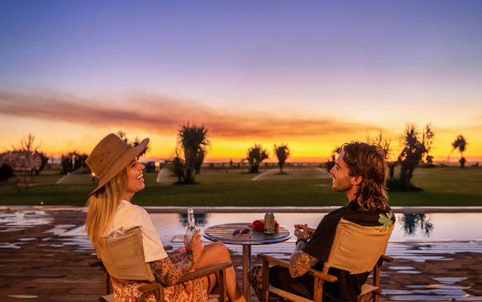 Couple enjoying sunset by pool at Top End Safari Camp, Finniss River.