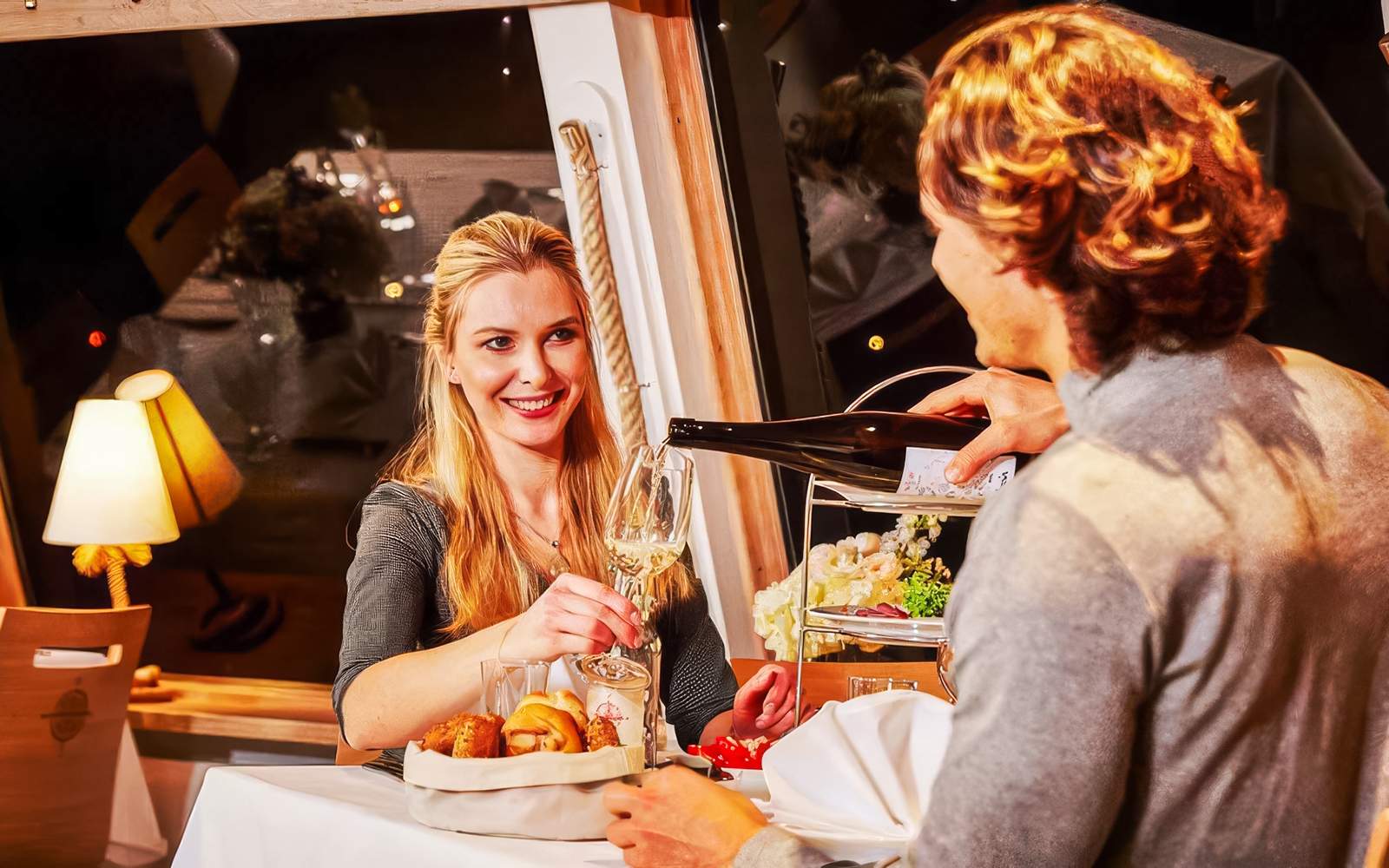 Couple dining on Danube River evening cruise, enjoying wine and appetizers.