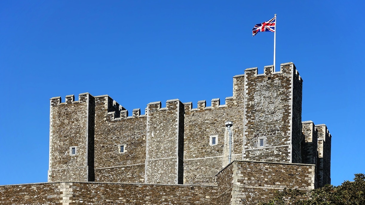Dover Castle Great Tower with Union Jack flag against blue sky.