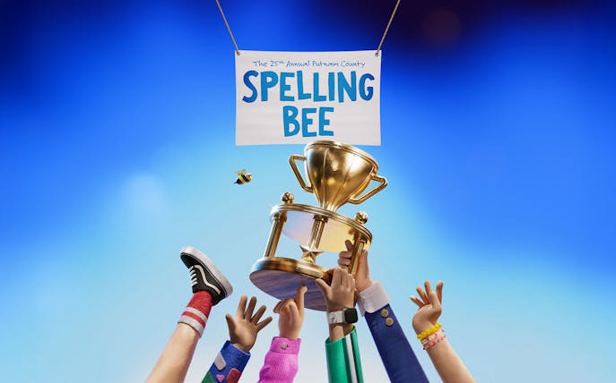 Hands holding a trophy under a sign for The 25th Annual Putnam County Spelling Bee.
