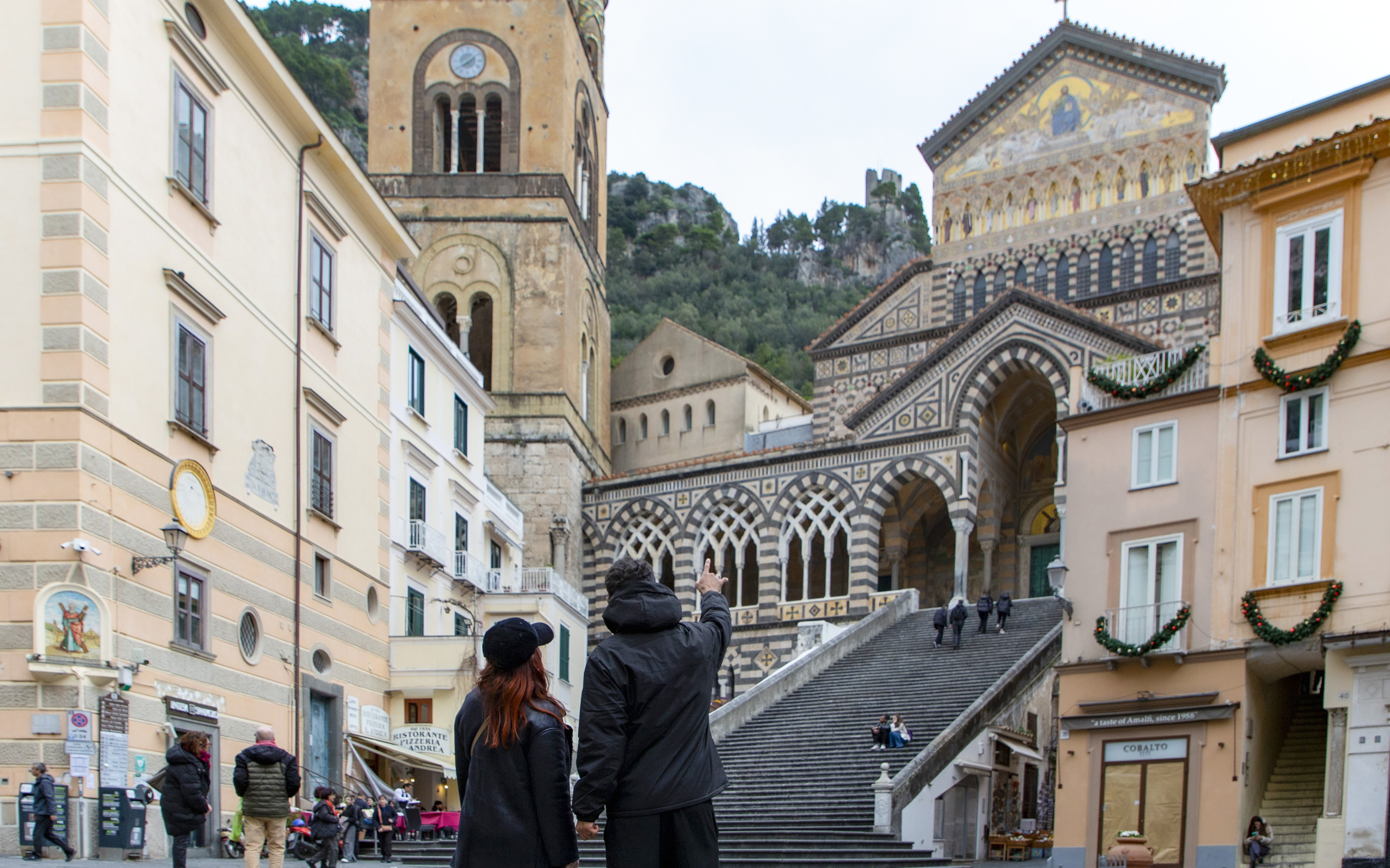 Amalfi Cathedral facade with people on steps in Amalfi, Italy.