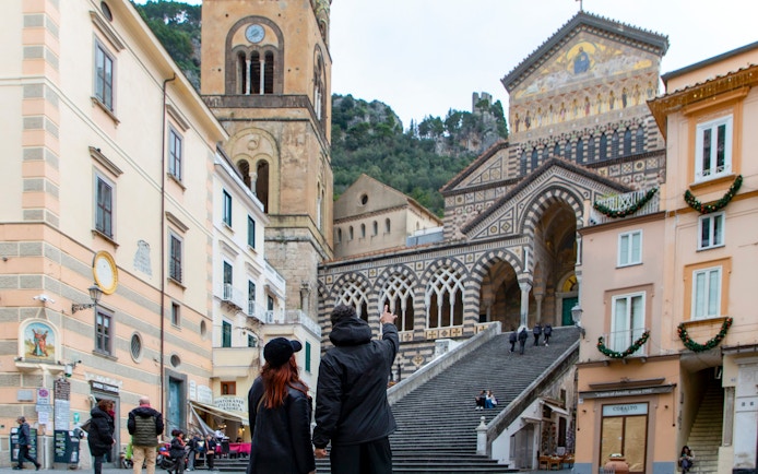 Amalfi Cathedral facade with people on steps in Amalfi, Italy.