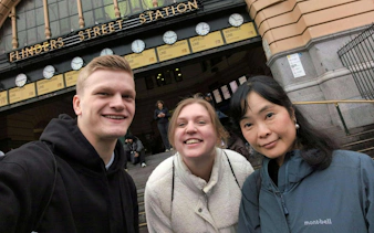 Flinders Street Station entrance with three people smiling, Melbourne Forgotten Red Diamond tour.