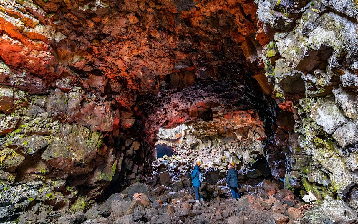 Guests exploring Raufarhólshellir Lava Cave's colorful rock formations, Iceland.