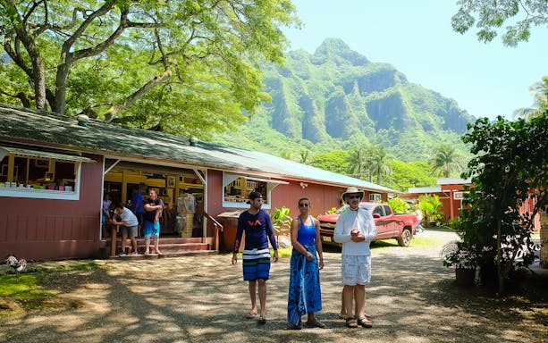 Visitors at a local shop with lush mountains in Oahu, Hawaii, part of the Oahu All-Inclusive Pass by Go City.