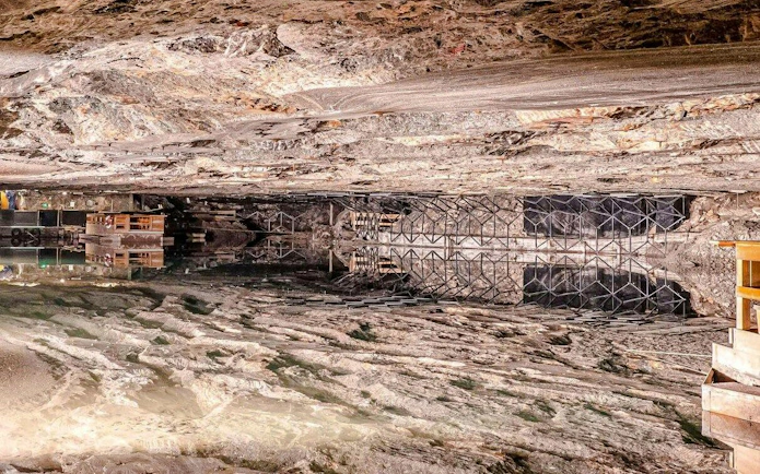 Inside view of Berchtesgaden Salt Mine with reflective underground lake and rock formations.