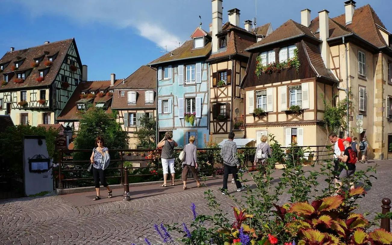 Colmar half-timbered houses with tourists walking on a bridge, Petite Venise, Colmar.