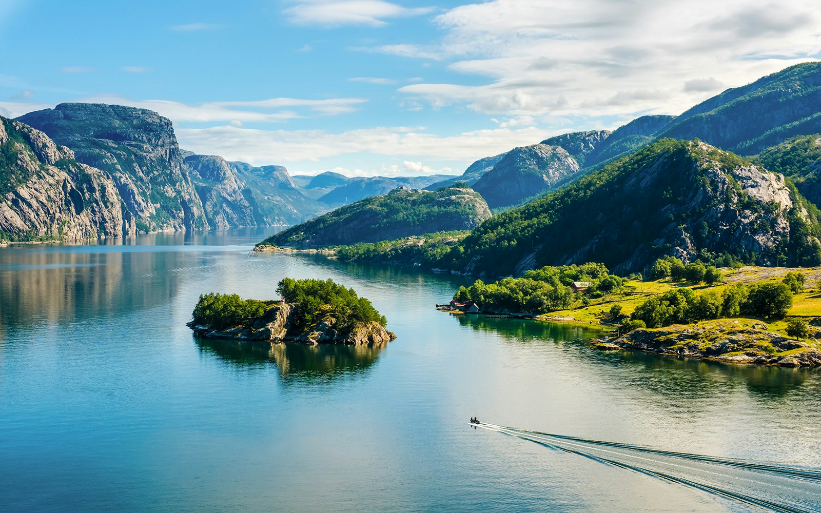 Lysefjord in Norway with lush green mountains and a small boat on the water.