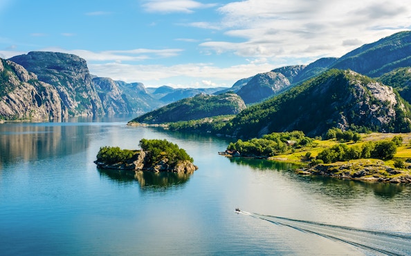 Lysefjord in Norway with lush green mountains and a small boat on the water.