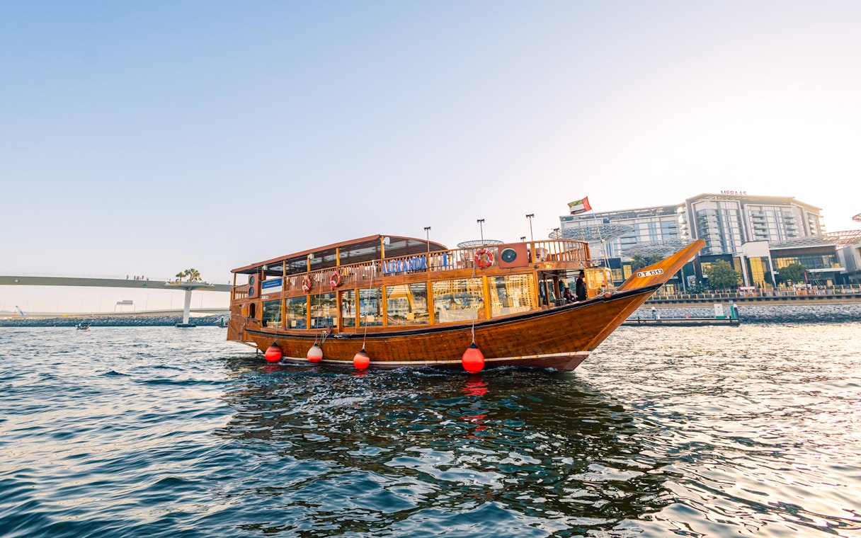 Dhow boat cruising near Dubai Marina during sunset, part of the Alexandra VIP Dhow Cruise experience.