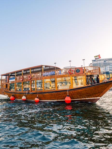 Dhow boat cruising near Dubai Marina during sunset, part of the Alexandra VIP Dhow Cruise experience.