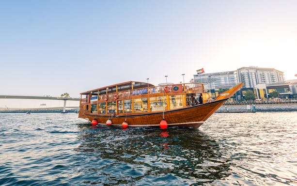 Dhow boat cruising near Dubai Marina during sunset, part of the Alexandra VIP Dhow Cruise experience.