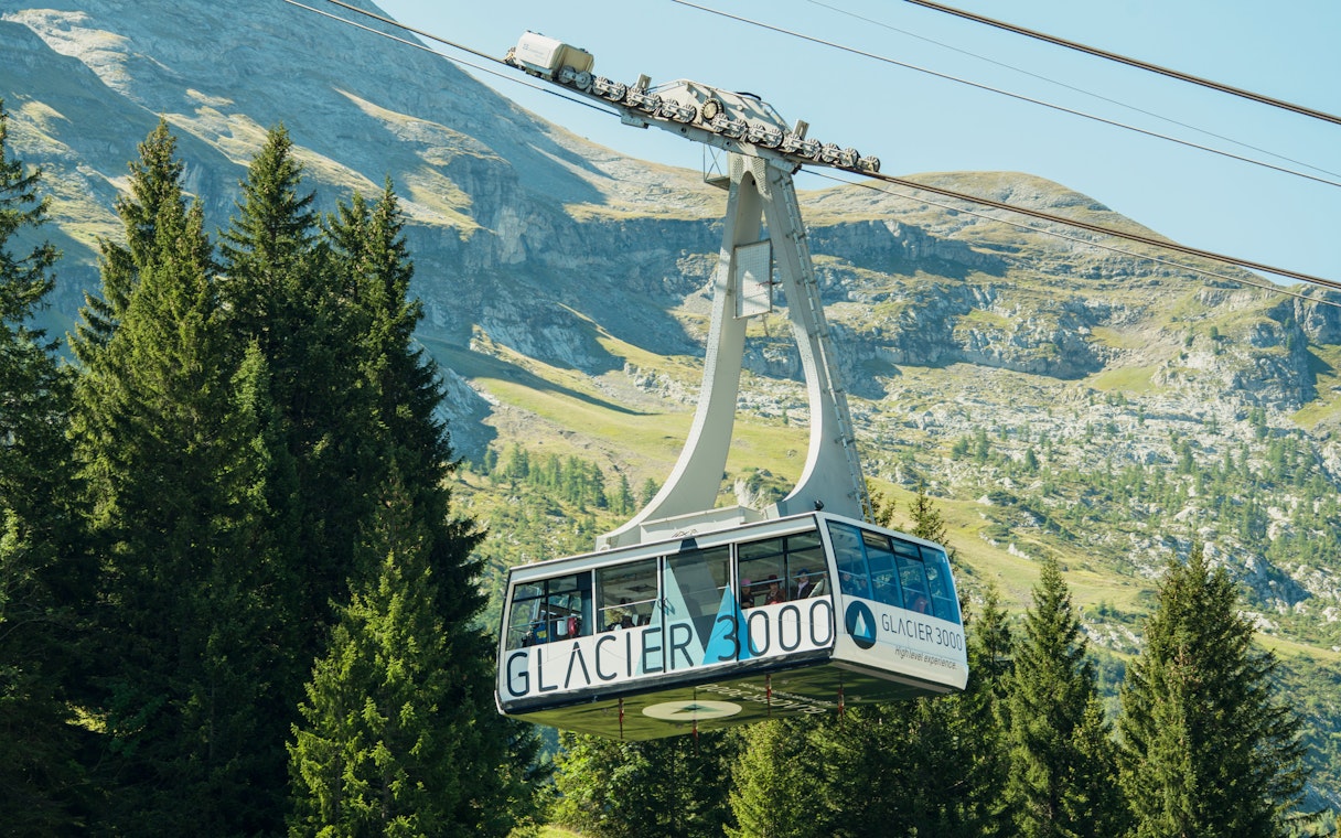 Cable car ascending to Glacier 3000 in Switzerland with mountain backdrop.