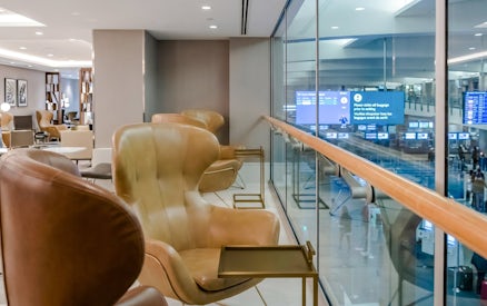 Seating area in Plaza Premium Lounge at Vancouver International Airport (YVR) with view of departure screens.