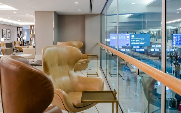 Seating area in Plaza Premium Lounge at Vancouver International Airport (YVR) with view of departure screens.