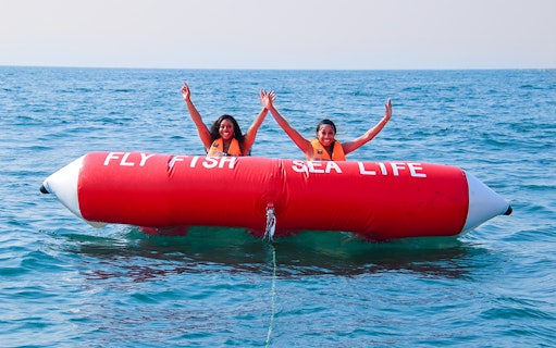 Two people enjoying a Fly Fish ride on the ocean.