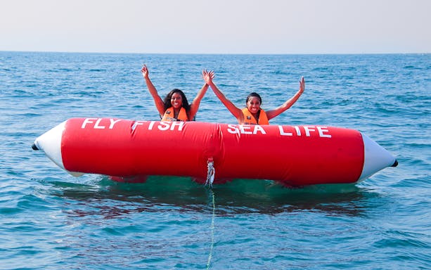 Two people enjoying a Fly Fish ride on the ocean.