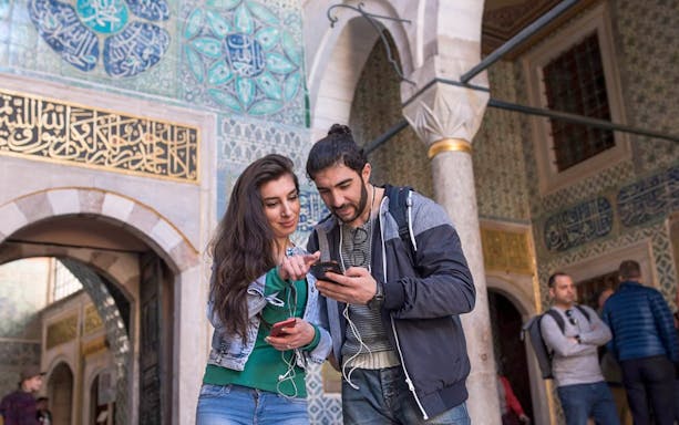 Visitors exploring Topkapi Palace with intricate tilework in Istanbul.
