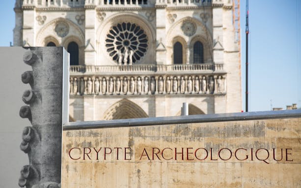 Notre-Dame Cathedral facade with Crypt Archeologique sign in Paris.