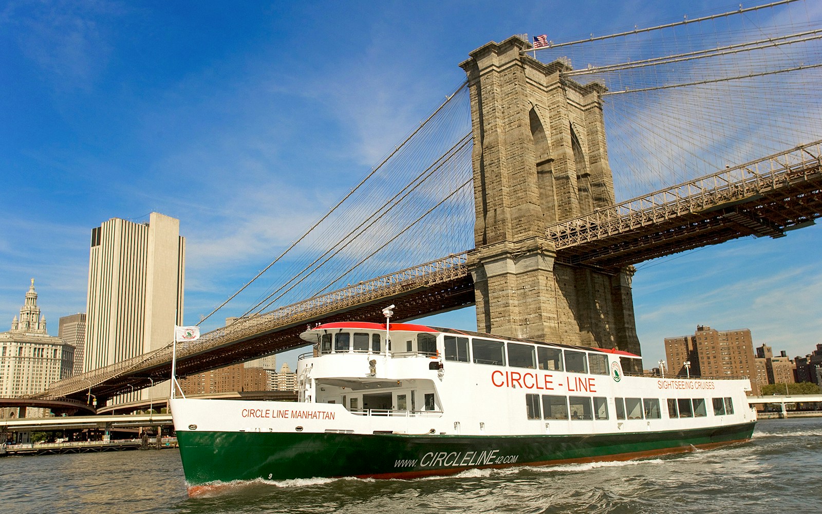 Tourists enjoying the Circle Line: 2hr NYC Harbor Lights Cruise with a view of the illuminated New York skyline at dusk