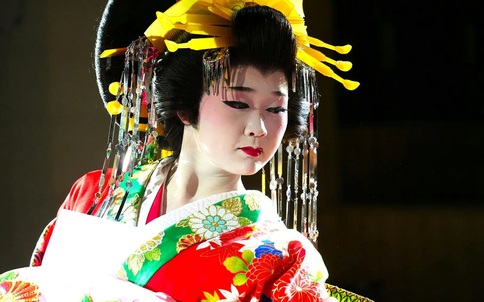 Traditional Japanese dancer in colorful kimono and elaborate headpiece.