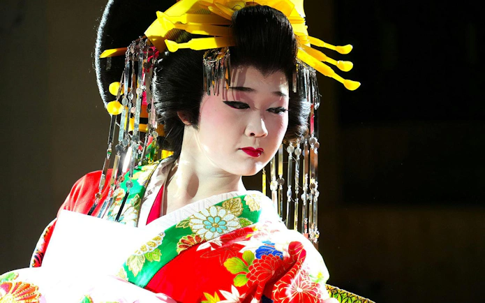 Traditional Japanese dancer in colorful kimono and elaborate headpiece.