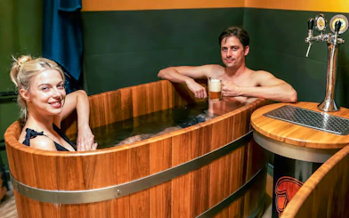 Couple enjoying beer spa in wooden tubs at Budapest's Lukács Thermal Bath.