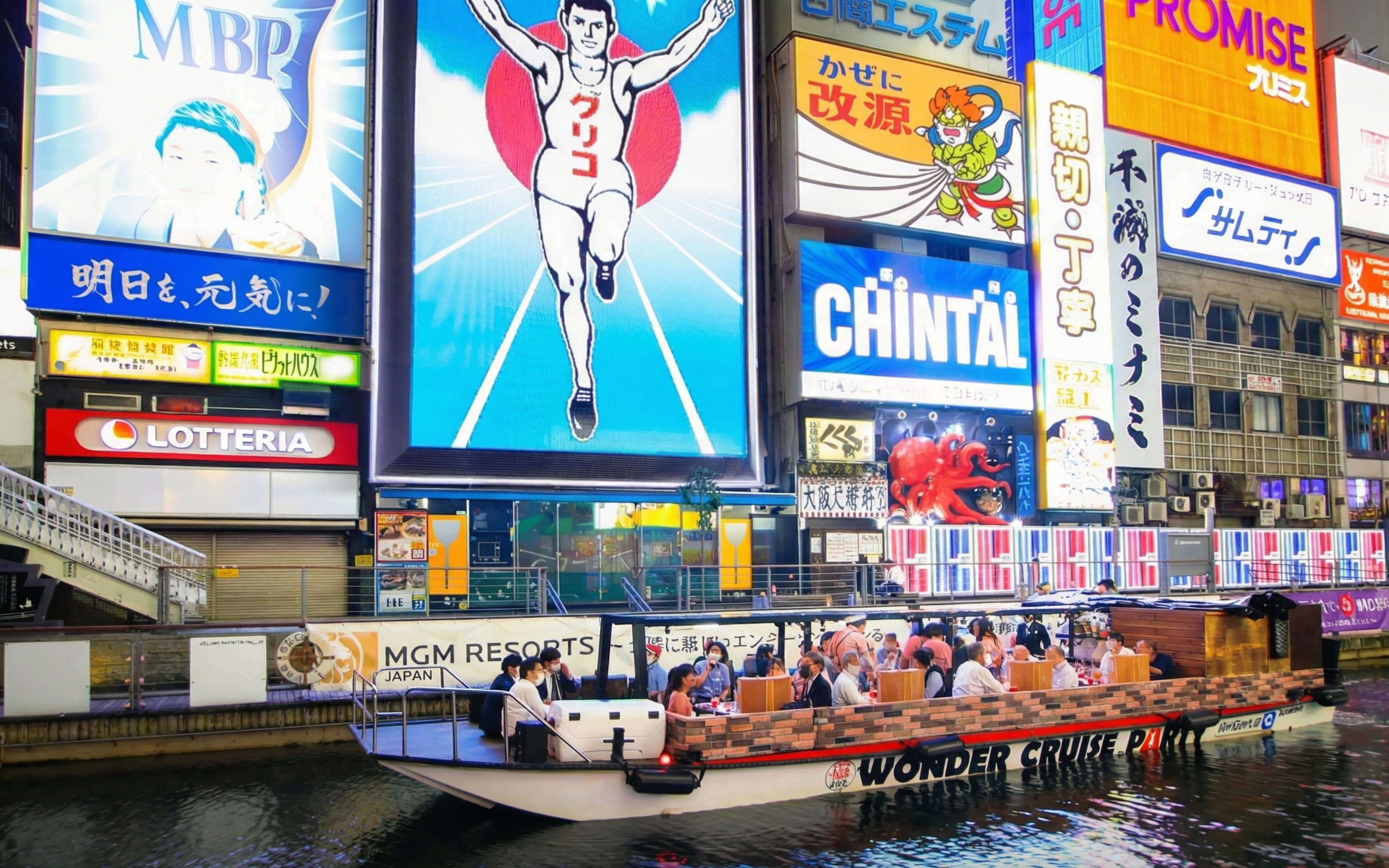 Dotonbori Wonder Cruise passing neon-lit billboards in Osaka at night.