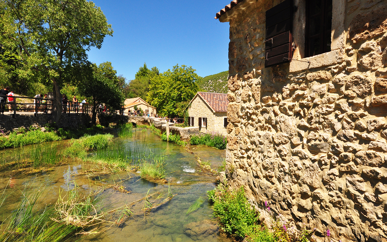 Traditional ethno village in Krka National Park, Croatia, showcasing rustic stone houses and lush greenery.