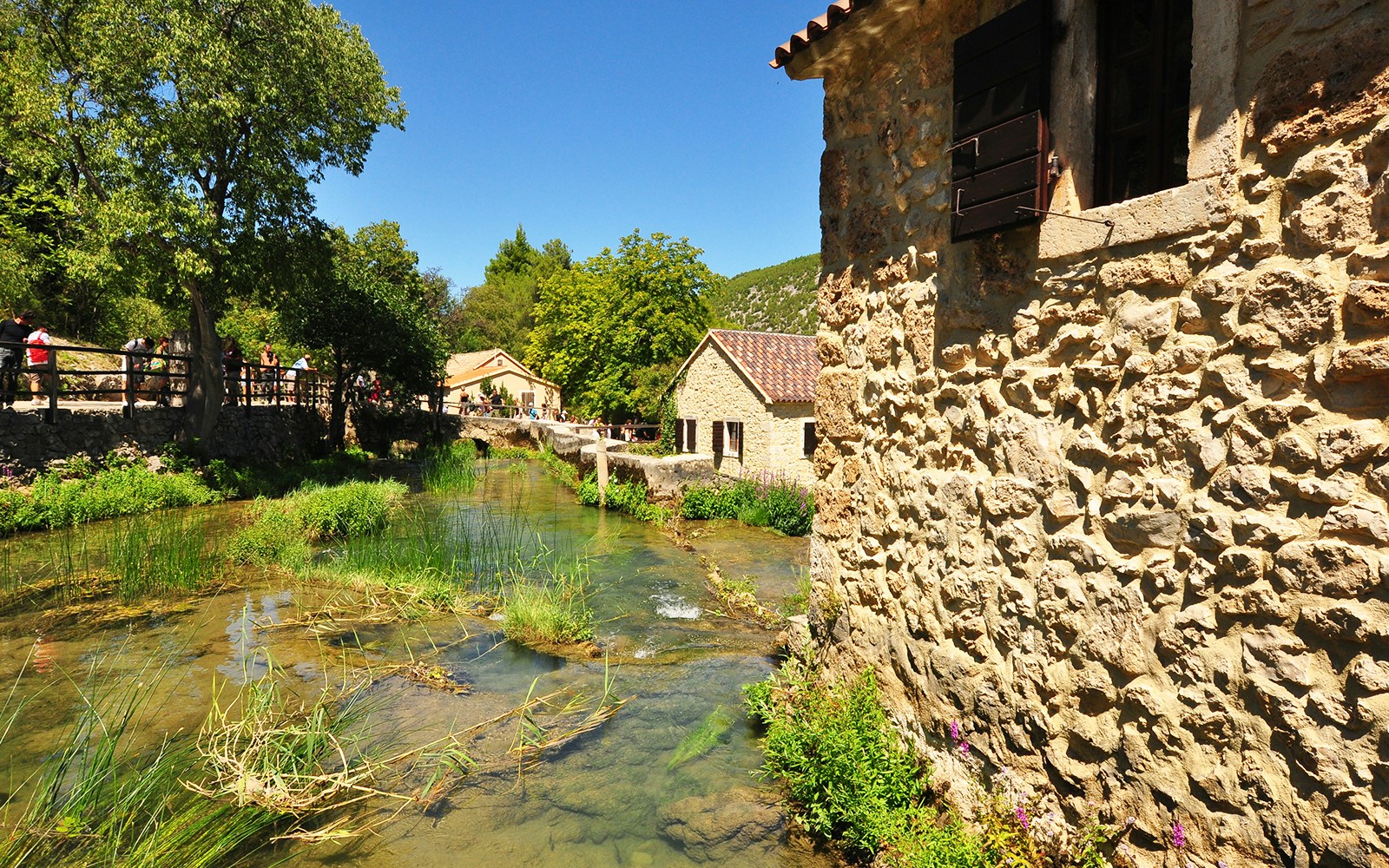 Traditional ethno village in Krka National Park, Croatia, showcasing rustic stone houses and lush greenery.