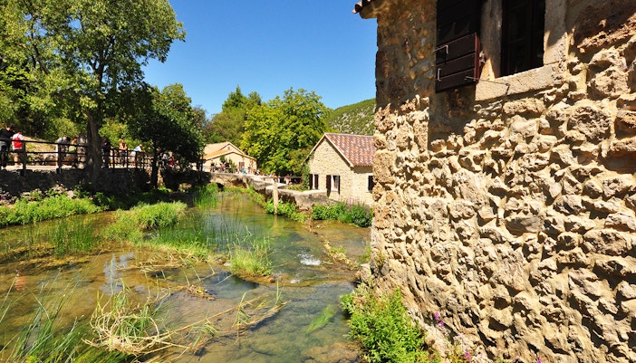 Traditional ethno village in Krka National Park, Croatia, showcasing rustic stone houses and lush greenery.