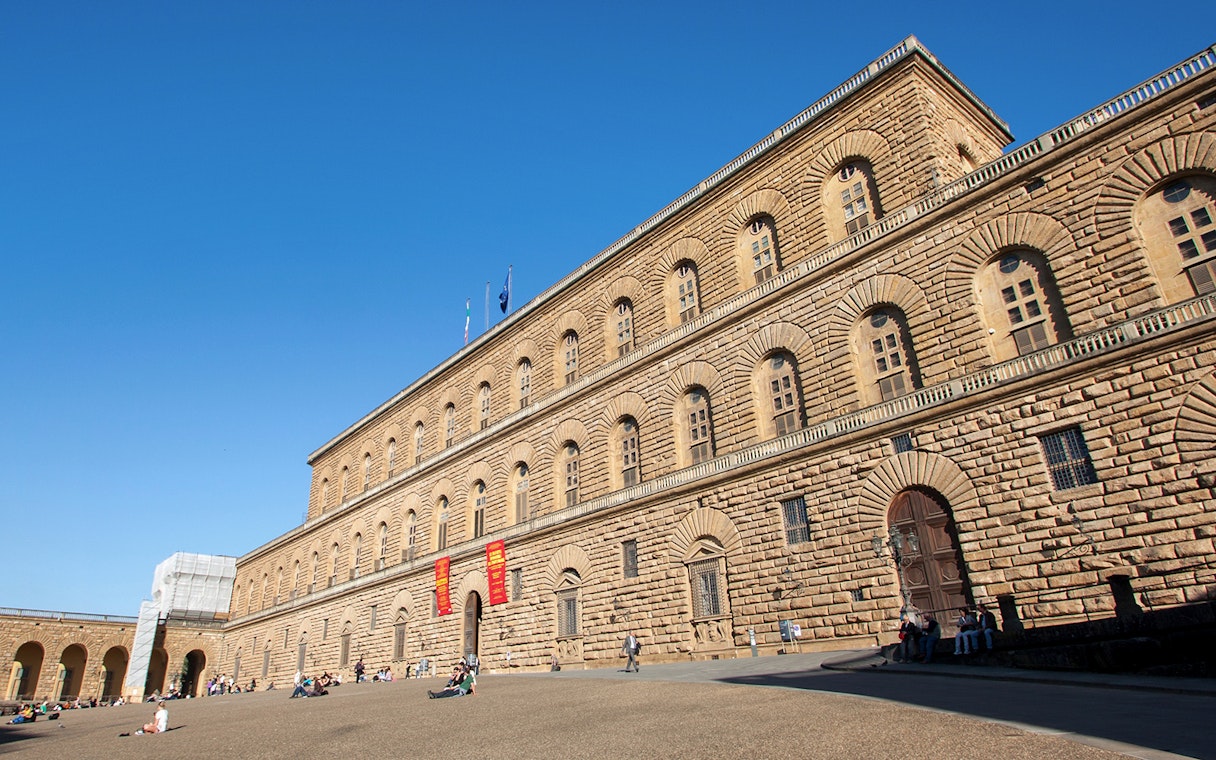 Palazzo Pitti facade in Florence with visitors on the courtyard.