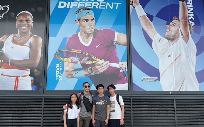 Group posing in front of tennis player posters on Melbourne Sports Guided Walking Tour.