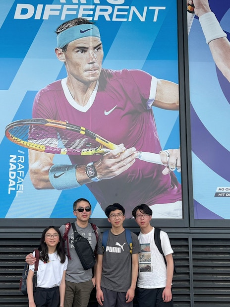Group posing in front of tennis player posters on Melbourne Sports Guided Walking Tour.
