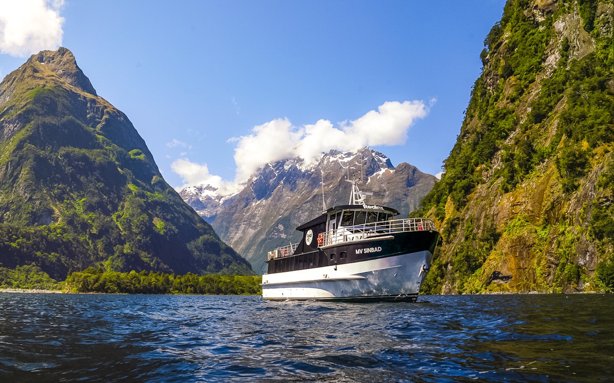 Sinbad cruise ship sailing through Milford Sound with scenic mountain backdrop.
