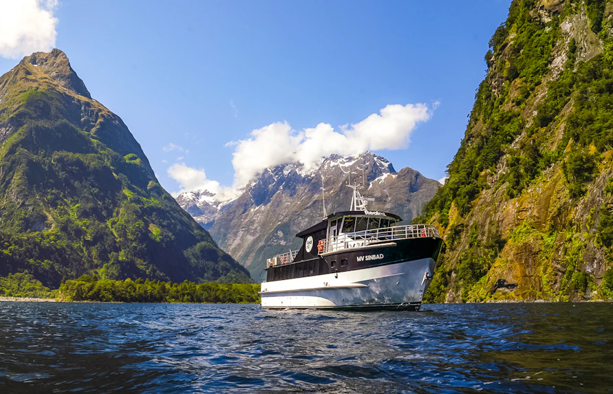 Sinbad cruise ship sailing through Milford Sound with scenic mountain backdrop.
