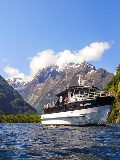 Sinbad cruise ship sailing through Milford Sound with scenic mountain backdrop.