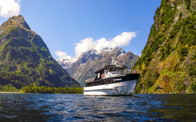 Sinbad cruise ship sailing through Milford Sound with scenic mountain backdrop.