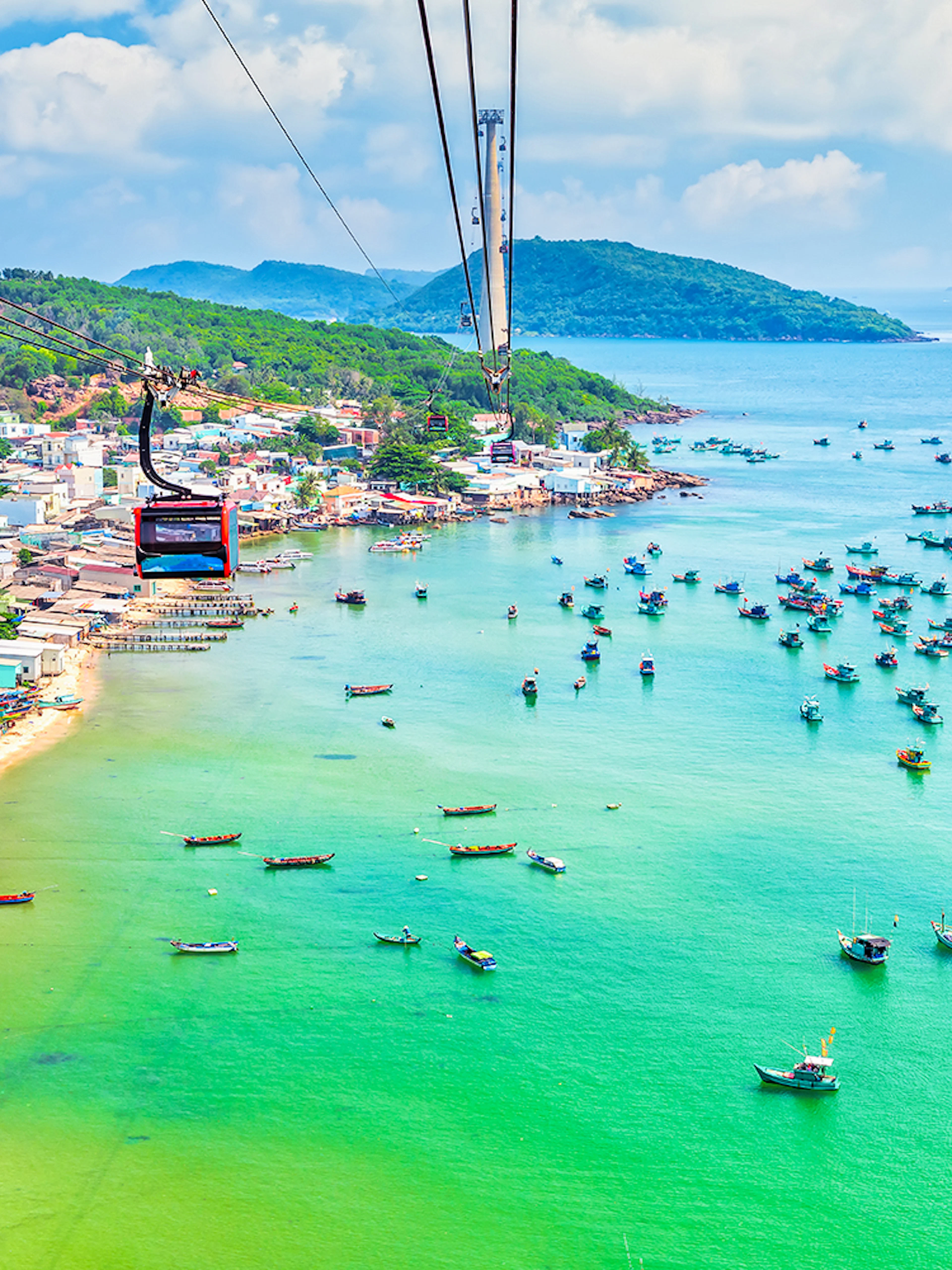 Cable car over Hon Thom Island, Phu Quoc, with colorful boats in turquoise water.