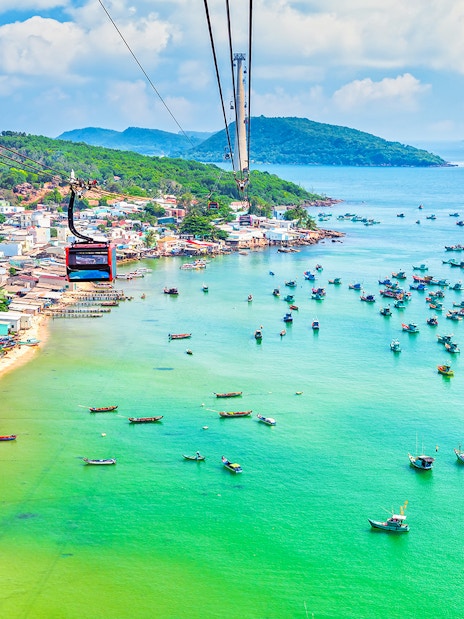 Cable car over Hon Thom Island, Phu Quoc, with colorful boats in turquoise water.