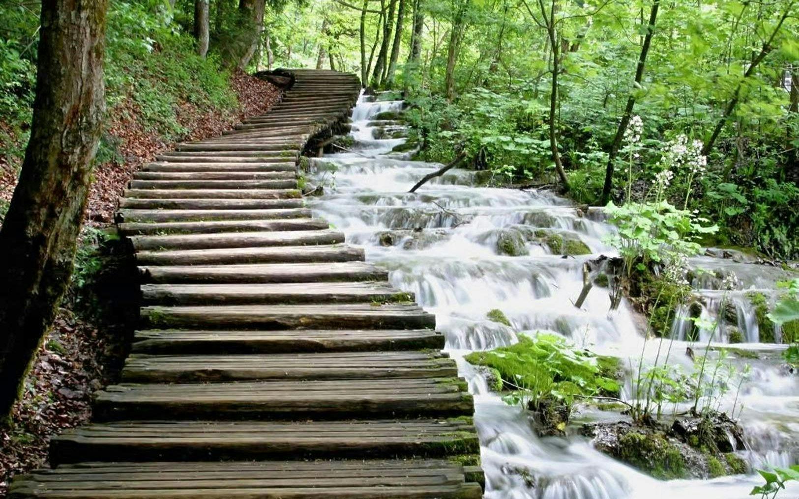 Wooden path alongside cascading waterfalls in Plitvice Lakes National Park.