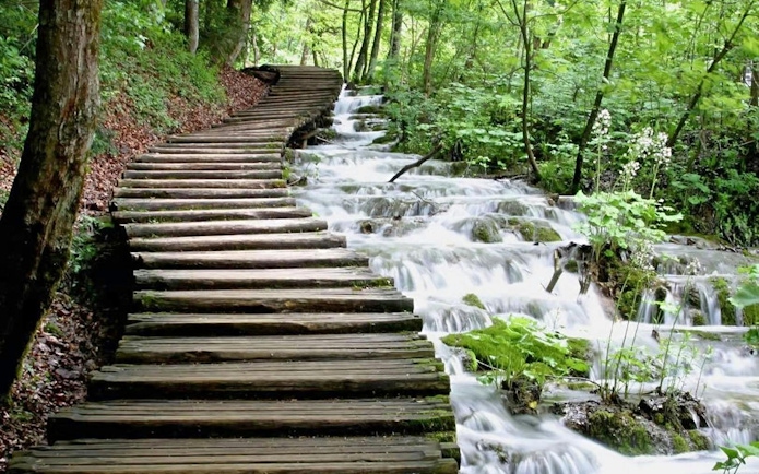 Wooden path alongside cascading waterfalls in Plitvice Lakes National Park.