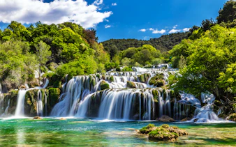 Waterfall cascading through lush greenery in Krka National Park, Croatia.