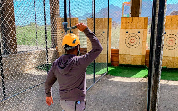 Person throwing axe at target in Hatta Wadi Hub activity area.