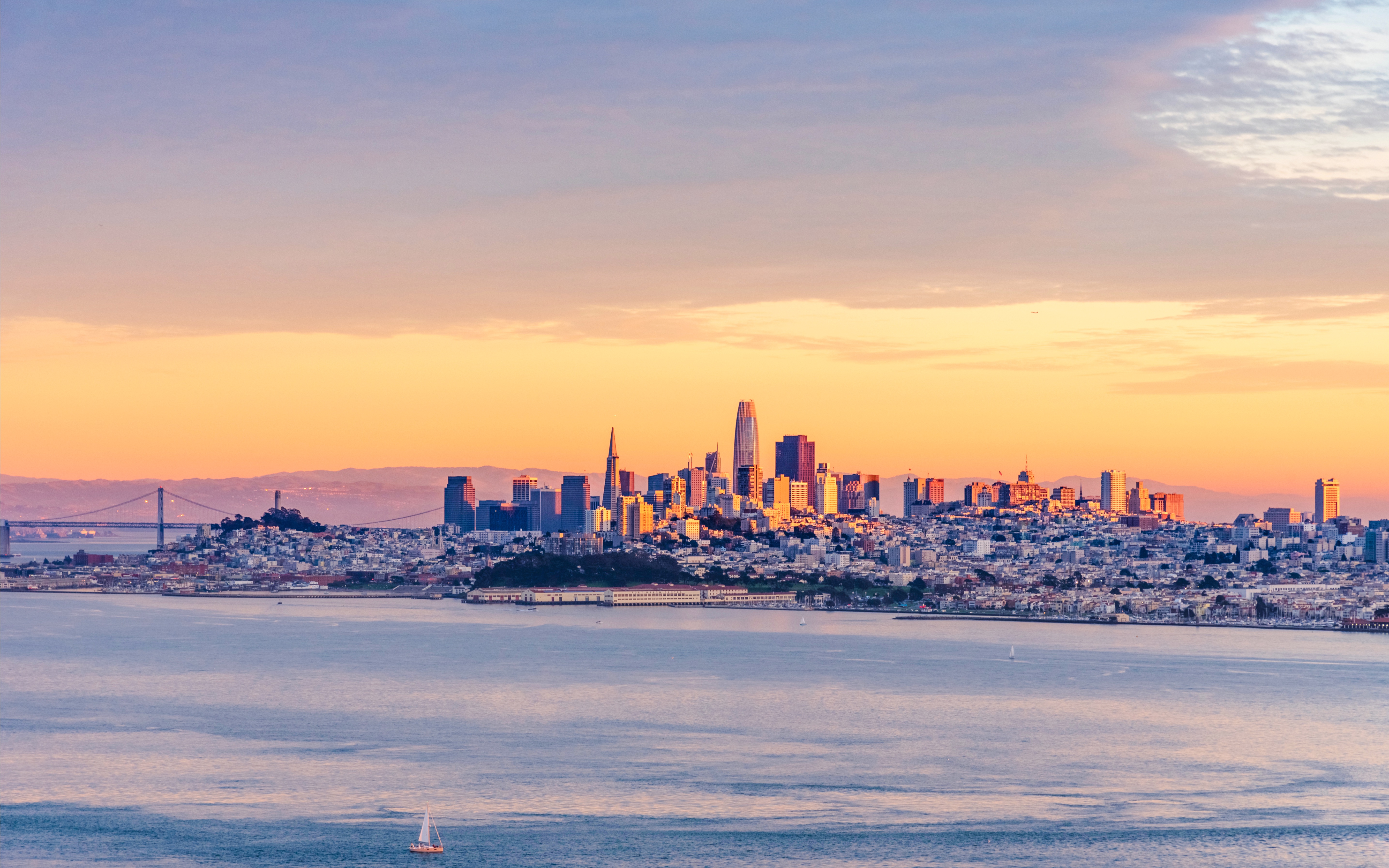 San Francisco skyline with Golden Gate Bridge at sunset.