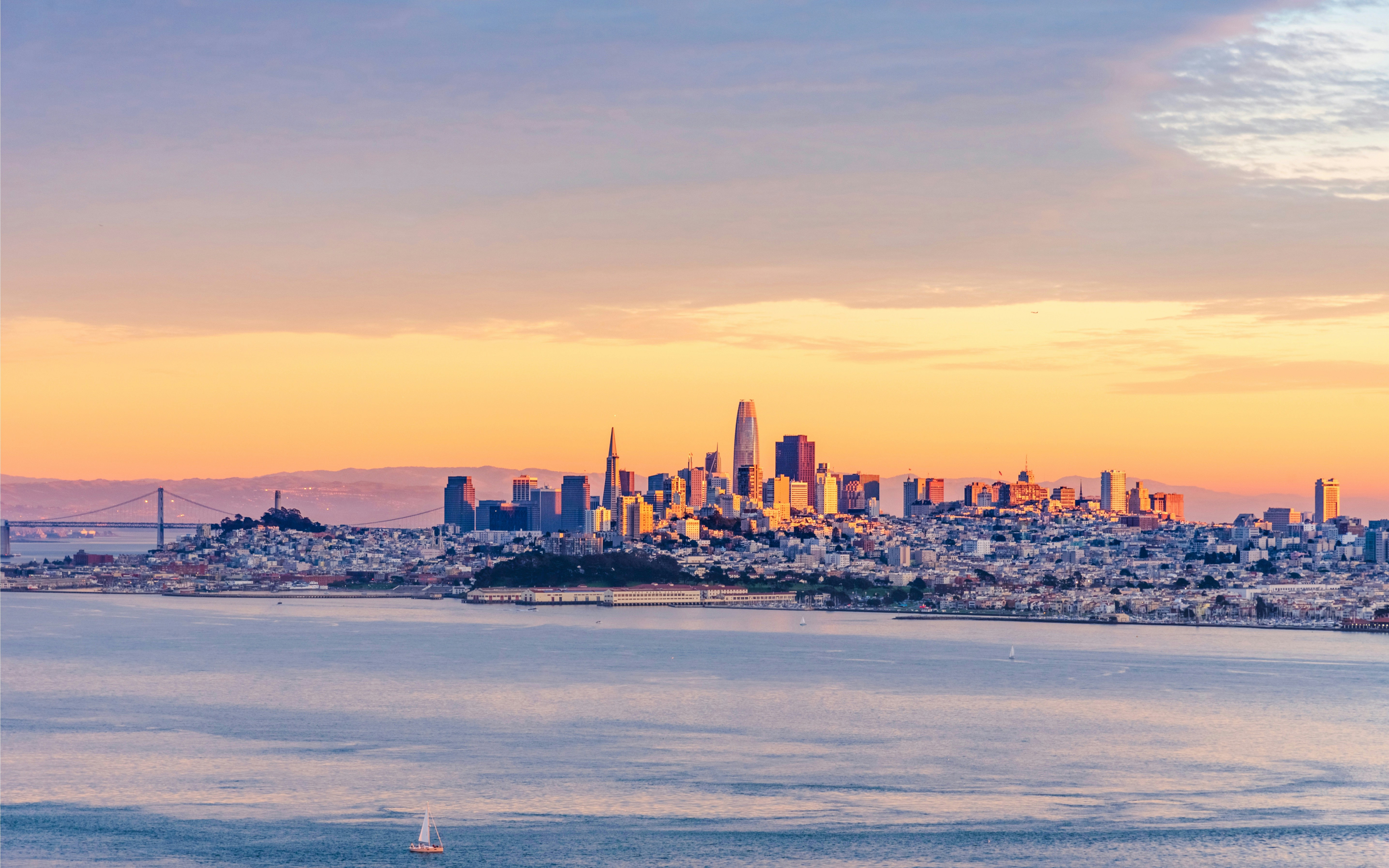 San Francisco skyline with Golden Gate Bridge at sunset.
