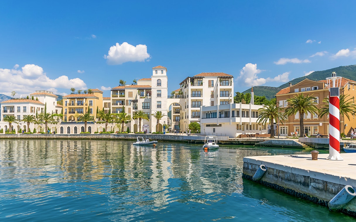 Bay of Tivat waterfront with colorful buildings and boats during Blue Cave tour.