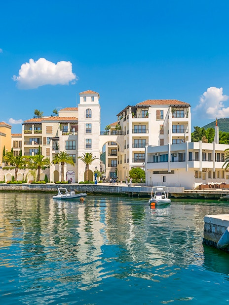 Bay of Tivat waterfront with colorful buildings and boats during Blue Cave tour.