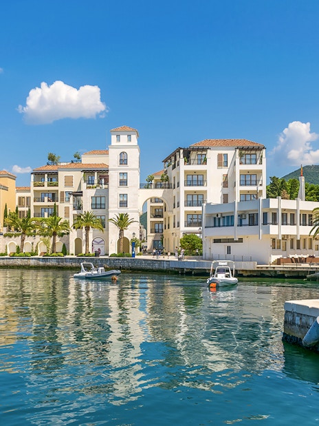 Bay of Tivat waterfront with colorful buildings and boats during Blue Cave tour.