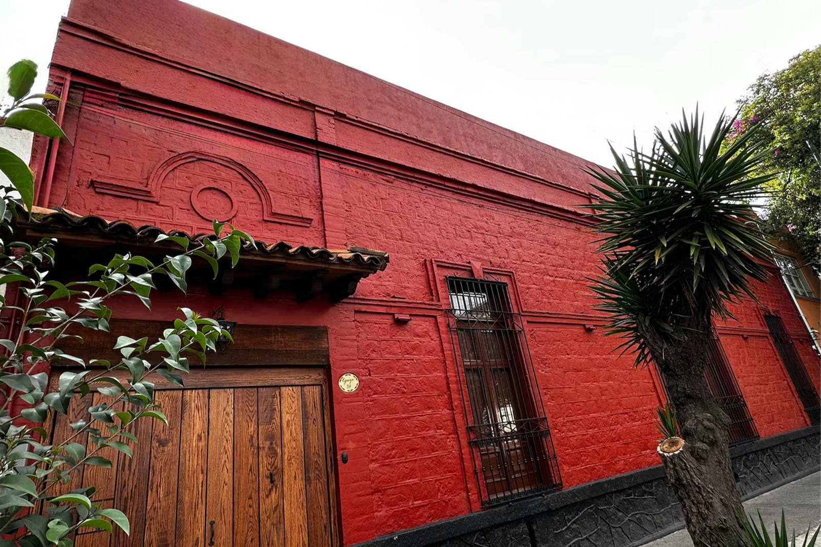 Frida Kahlo's red house exterior with wooden door and barred windows in Mexico City.